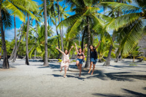 women skipping on a beach surrounded by palm trees celebrating their wellness journey through Ginger Hill Carms