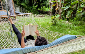 someone laying in a hammock reading a book enjoying their leisure time to relax and rest 
